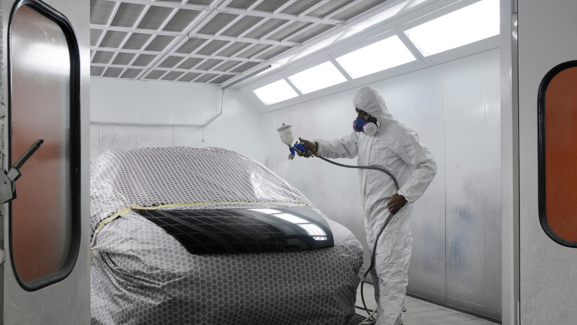 Automotive painter working inside a professional spray booth